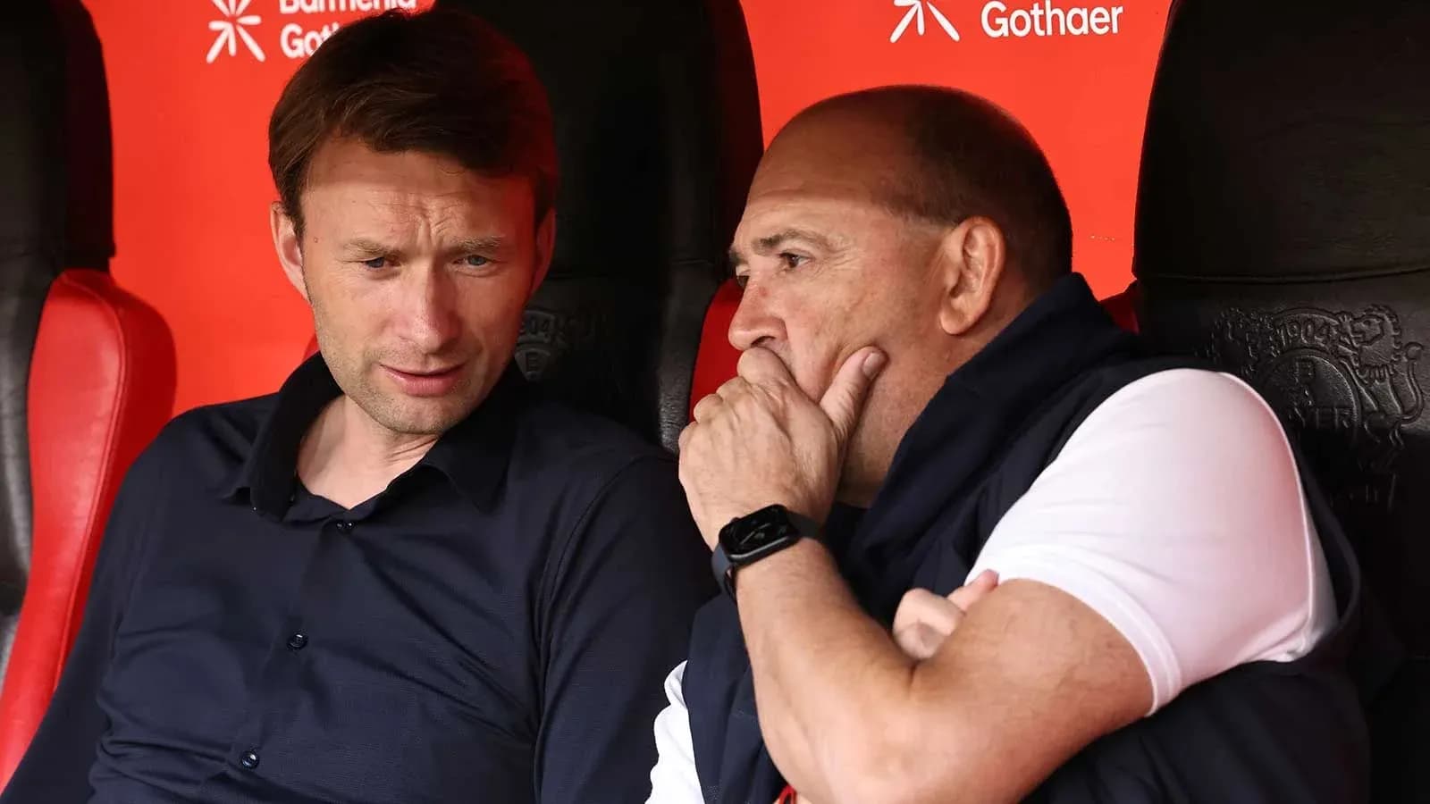 Two coaches discussing strategies on the bench