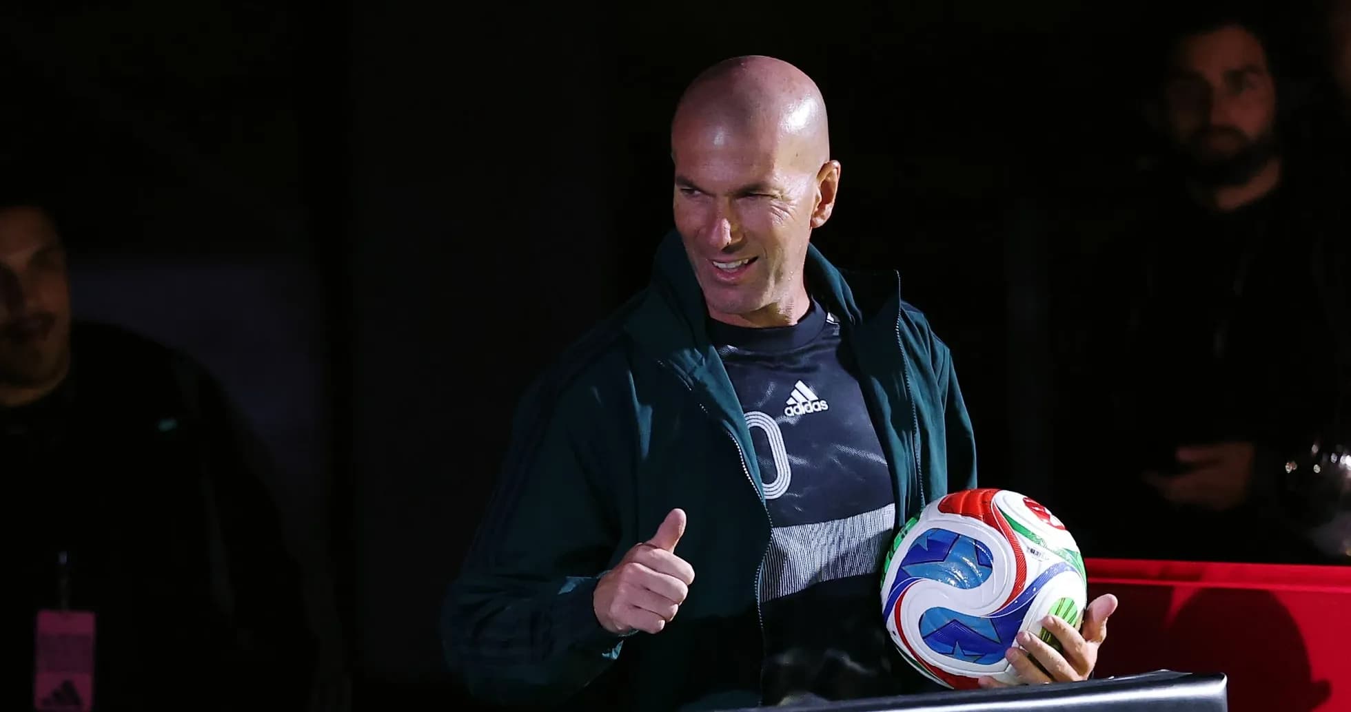 Zinedine Zidane holding a soccer ball and smiling