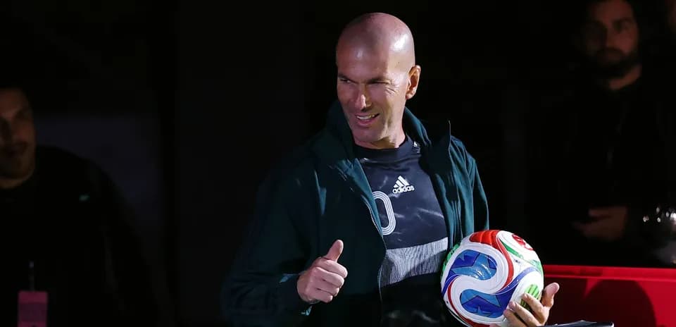Zinedine Zidane holding a soccer ball and smiling