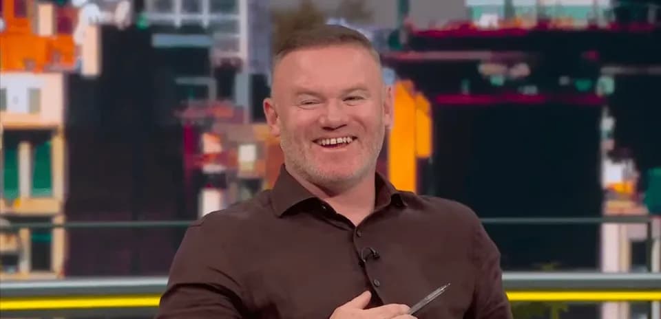 Presenter smiling while holding a pen on set