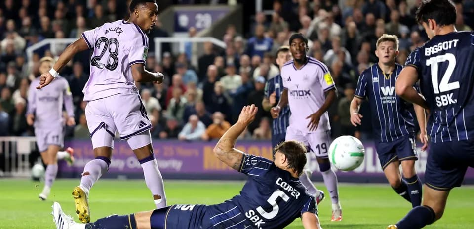 Player in purple jersey scoring against fallen defender