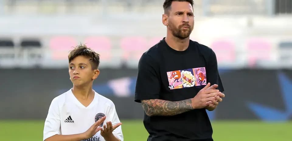 Lionel Messi and a young boy clapping on field