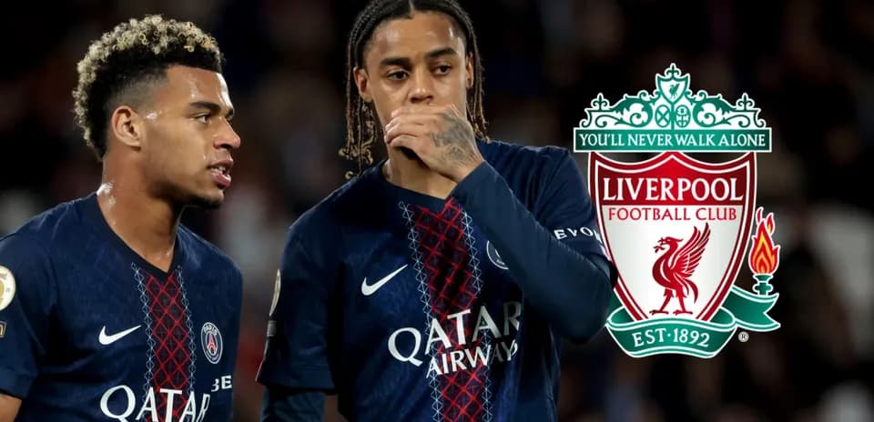 Two players discussing during a match with Liverpool logo