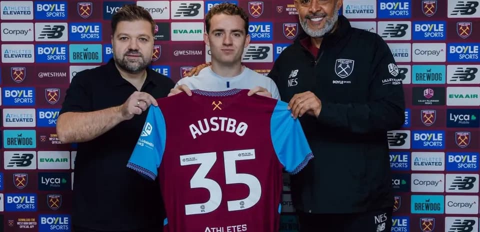 Player holding jersey during signing ceremony with staff