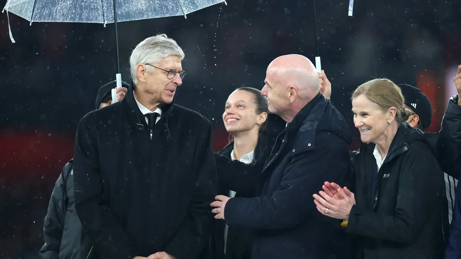 Group of officials conversing under an umbrella