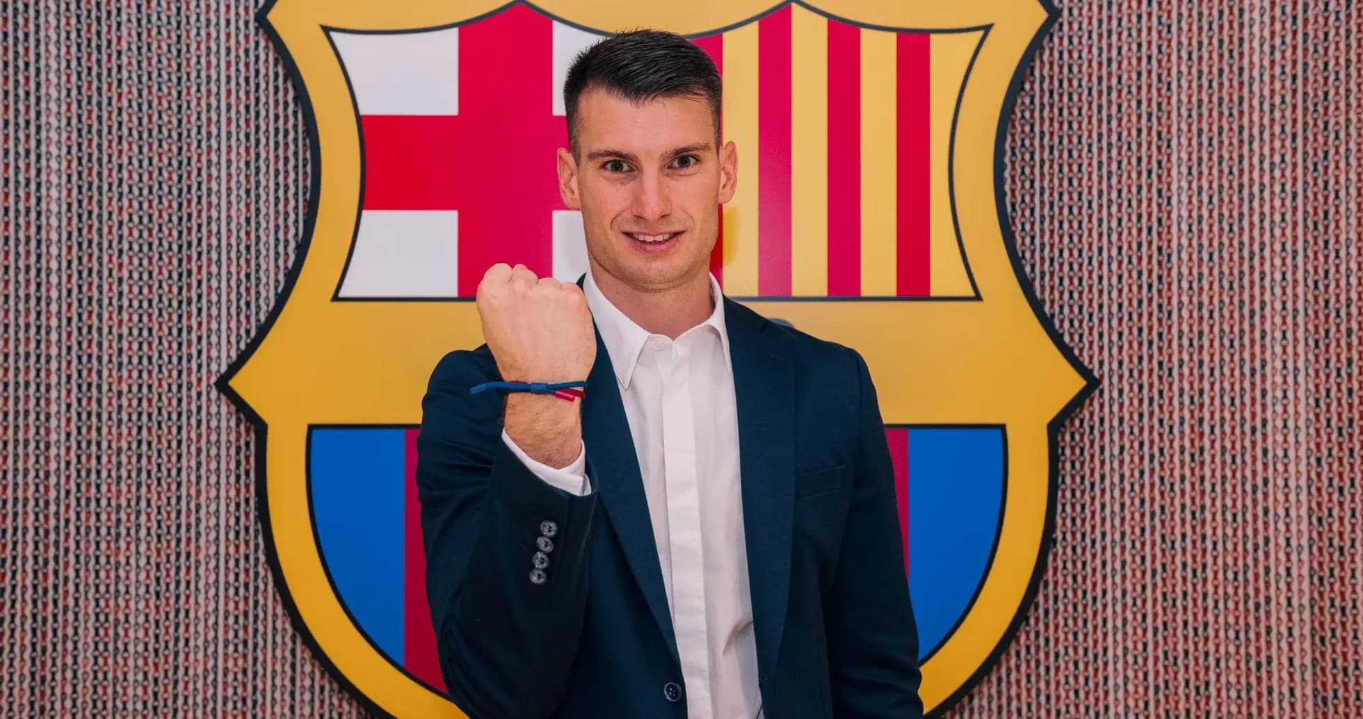 Player posing with fist raised in front of FC Barcelona logo