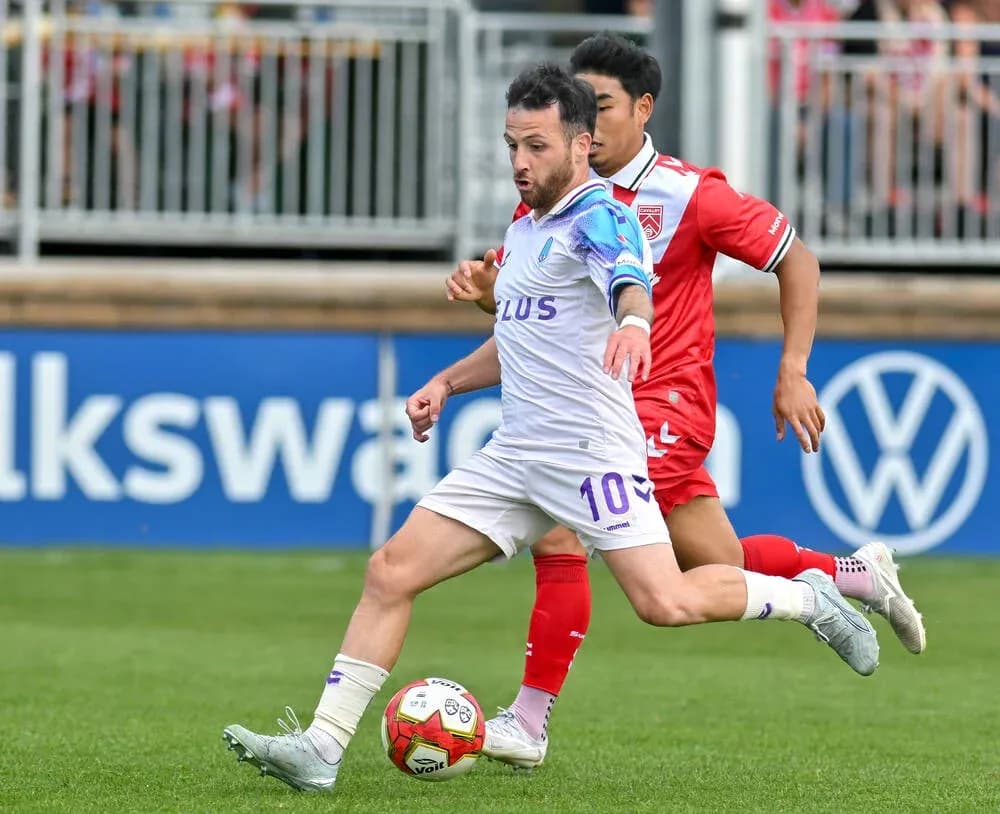 Cavalry FC player dribbling against Pacific FC opponent