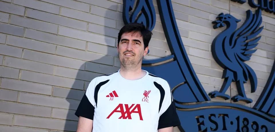 Man in Liverpool FC training gear by club logo