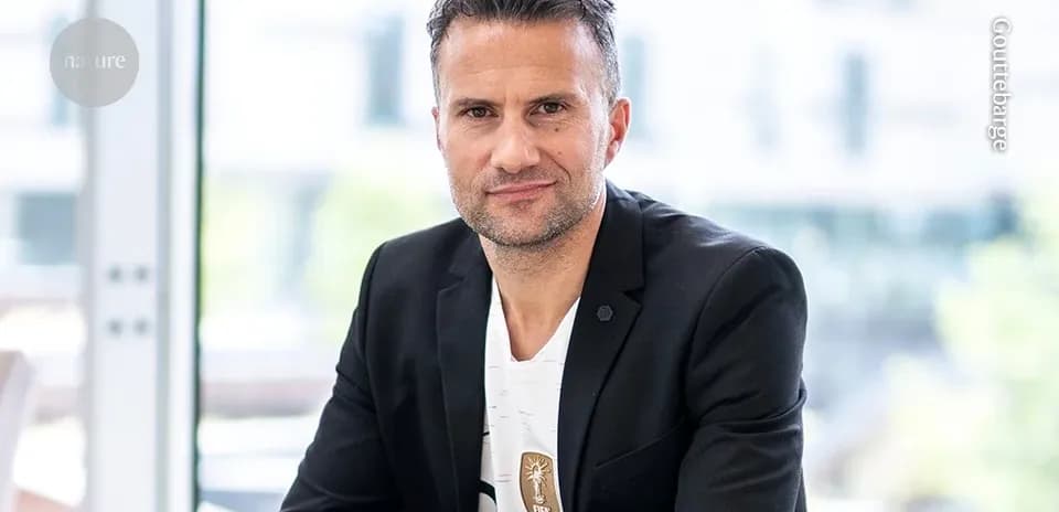 Man in a suit sitting indoors, looking at camera