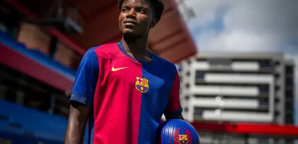 Player in Barcelona jersey holding a soccer ball