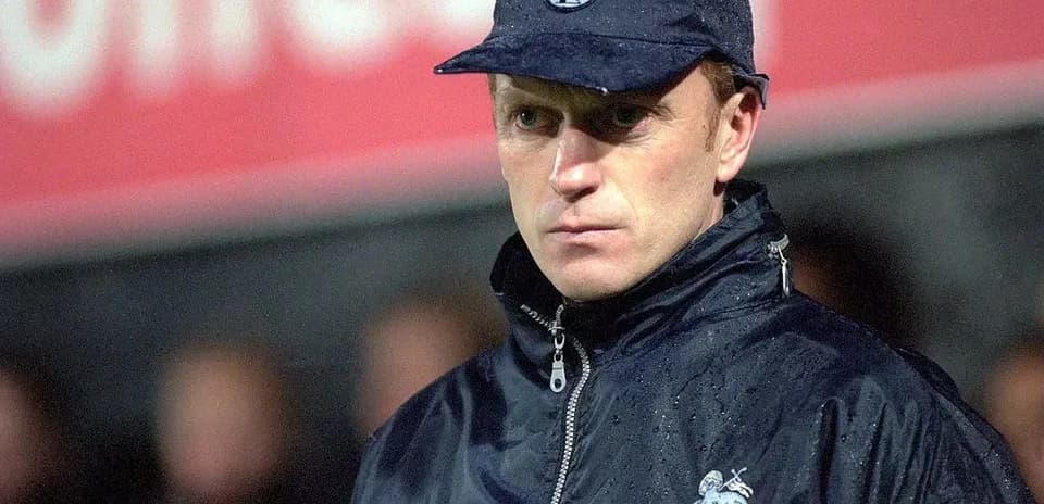 Coach observing match in rain with team jacket