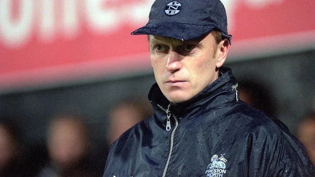 Coach observing match in rain with team jacket