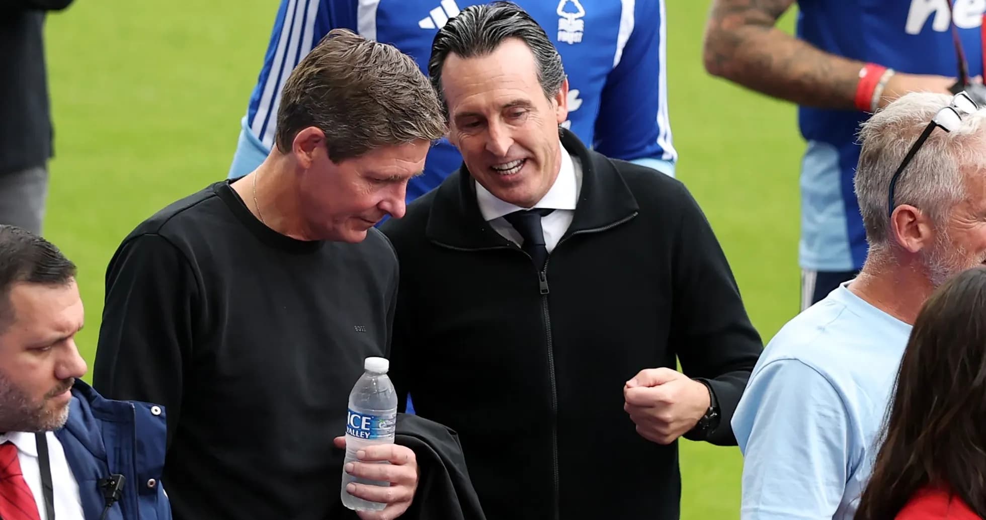 Two coaches conversing on the pitch sidelines