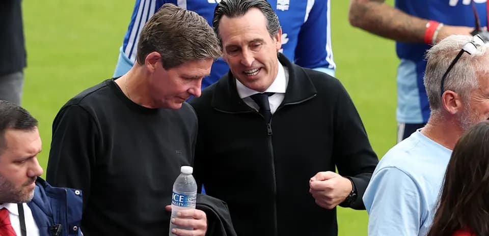 Two coaches conversing on the pitch sidelines