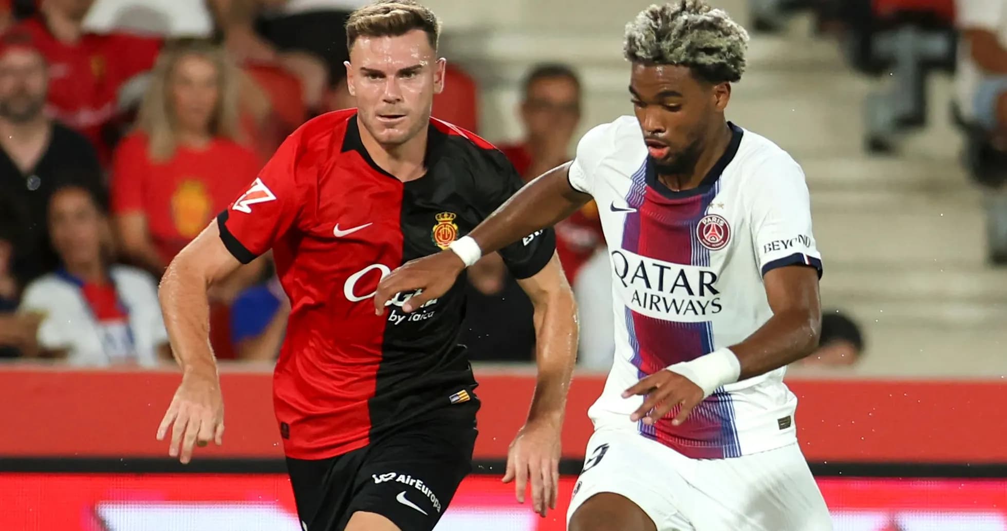 Players from Mallorca and PSG competing for the ball