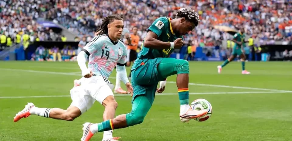 Cameroon player dribbling past opponent during match