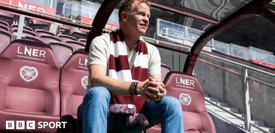 Manager sitting in stadium dugout with scarf