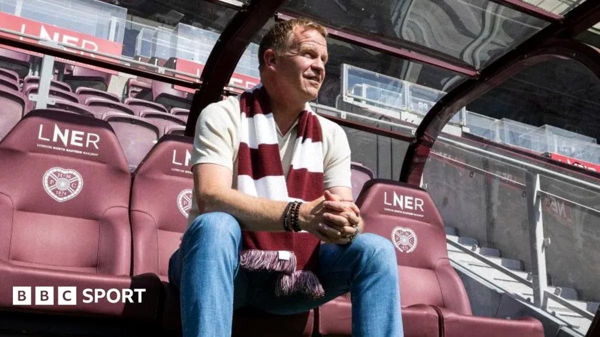 Manager sitting in stadium dugout with scarf
