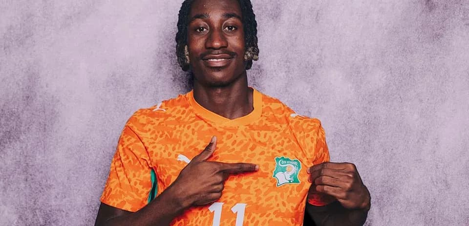 Player wearing orange jersey pointing to crest