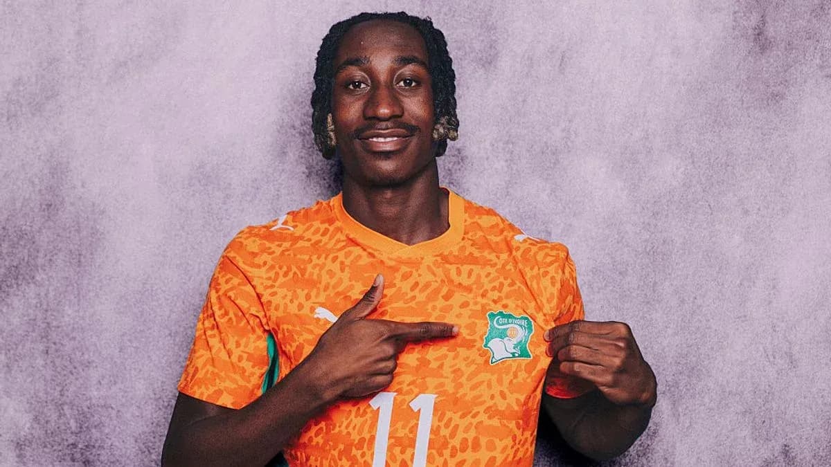 Player wearing orange jersey pointing to crest