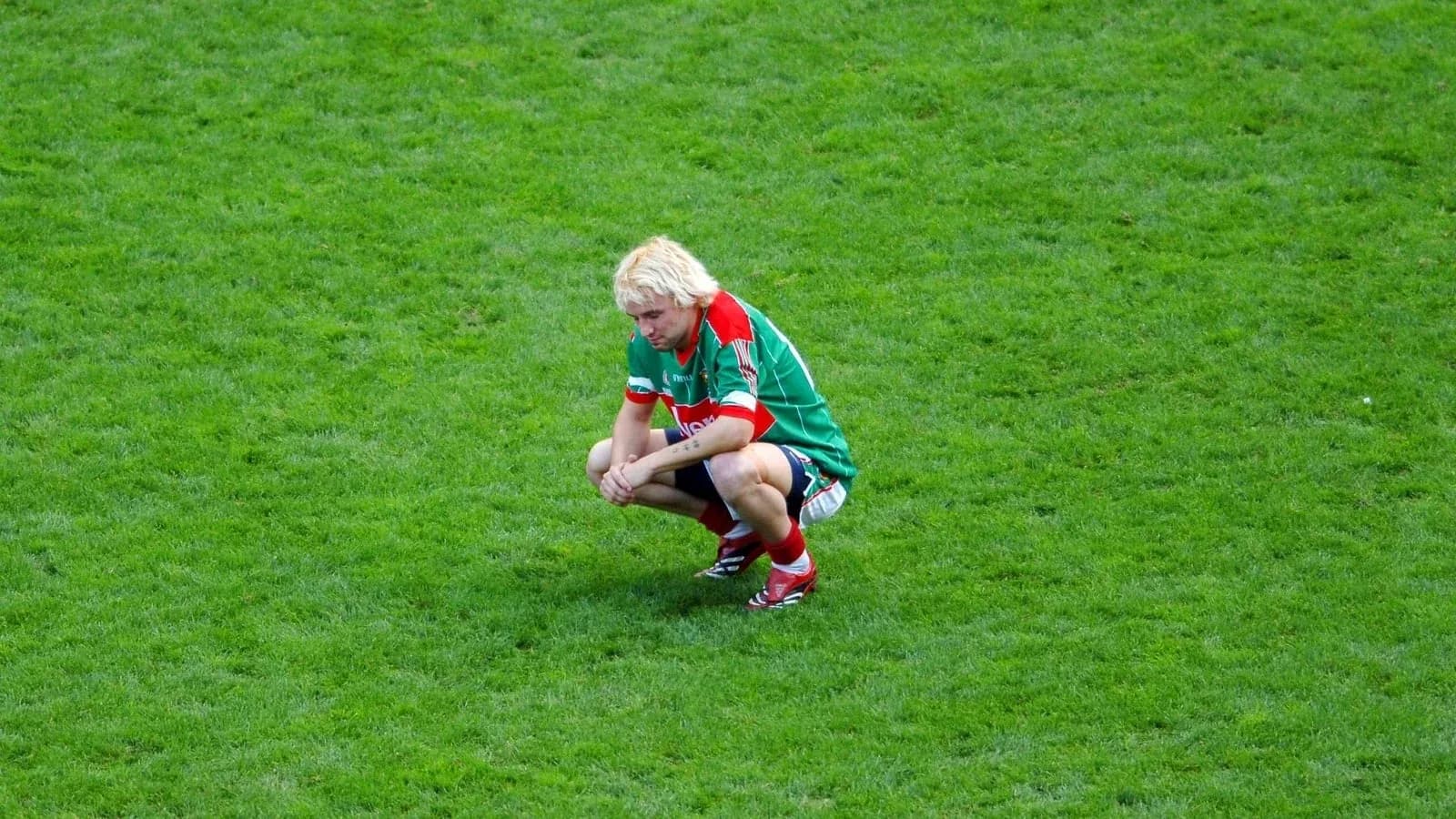 Player squatting on the field after a match