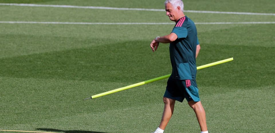 Coach walking on training pitch with training pole