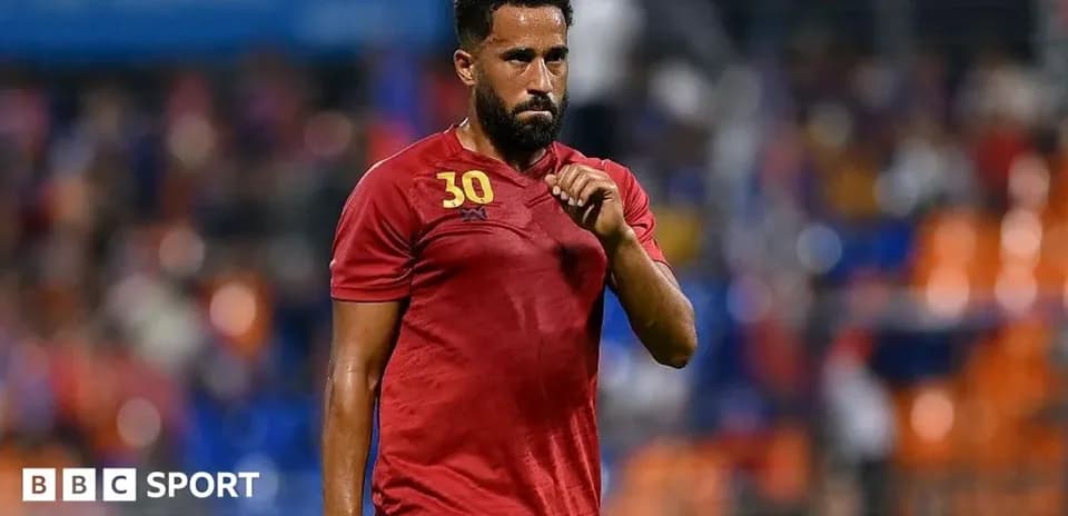 Player in red jersey walking on the pitch