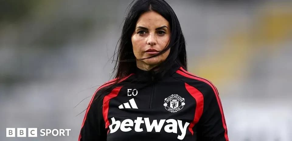 Coach wearing Manchester United tracksuit on pitch