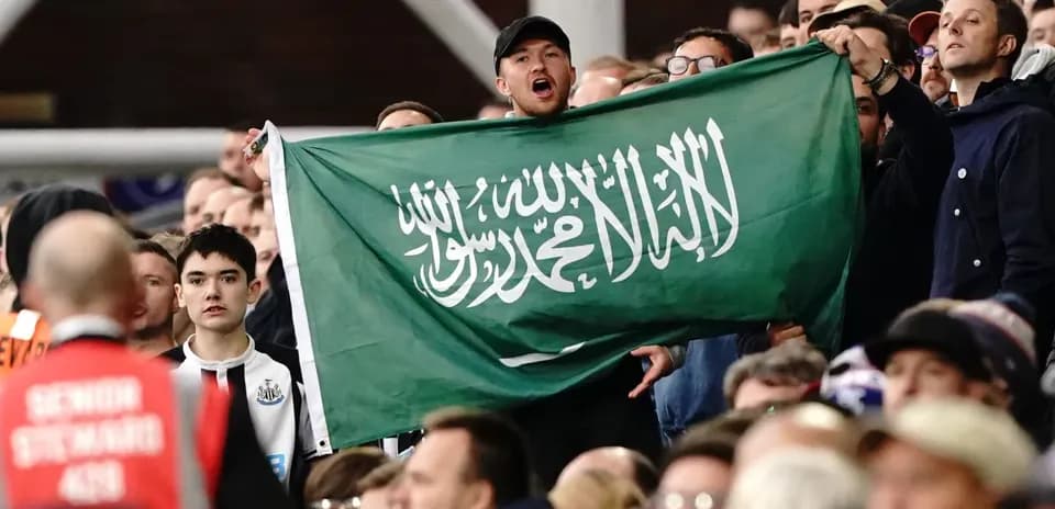 Fans holding a Saudi Arabian flag in stadium