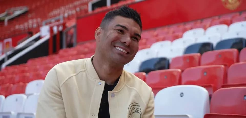 Player seated in empty stadium stands, smiling