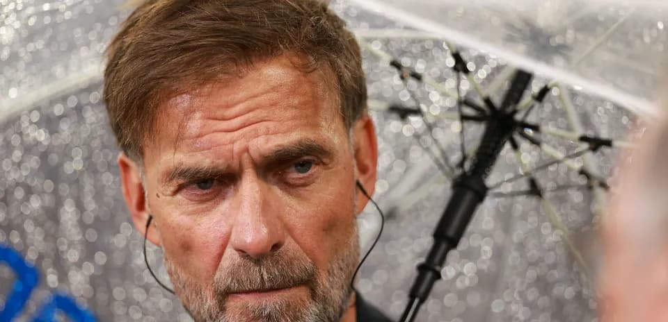 Coach speaking under an umbrella during rain