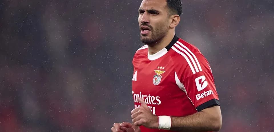 Player in red Benfica kit running on rainy pitch