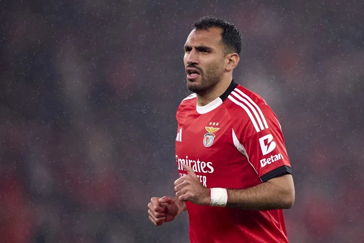 Player in red Benfica kit running on rainy pitch