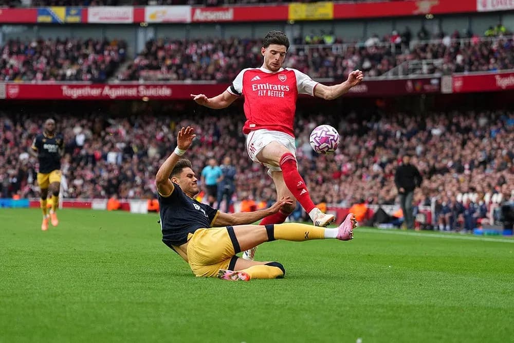 Arsenal player challenging West Ham opponent during match