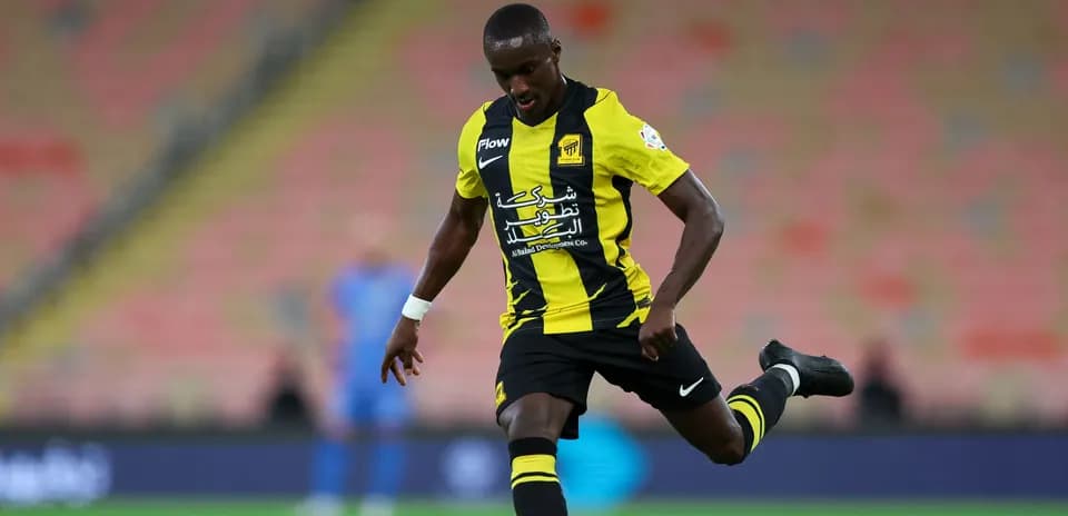 Player in black and yellow kit kicking a soccer ball