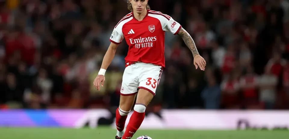 Player in Arsenal kit dribbling a soccer ball