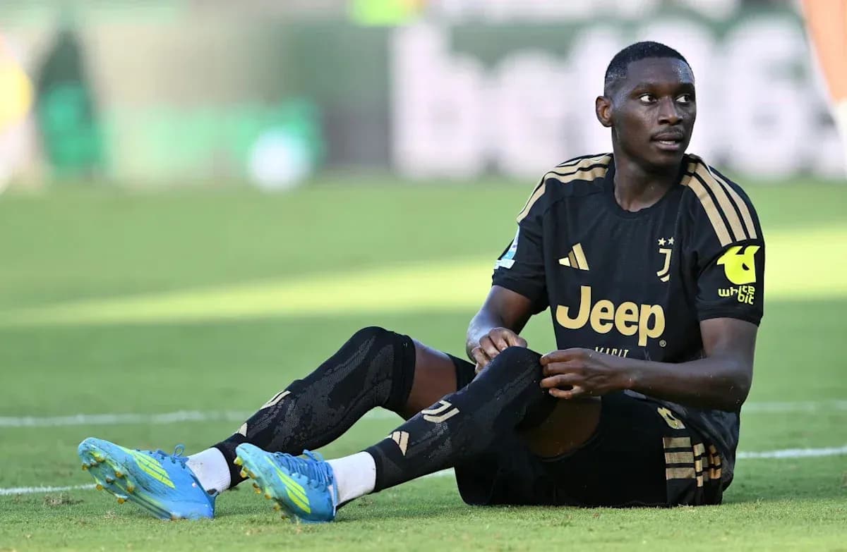 Player sitting on field during match, wearing Juventus kit