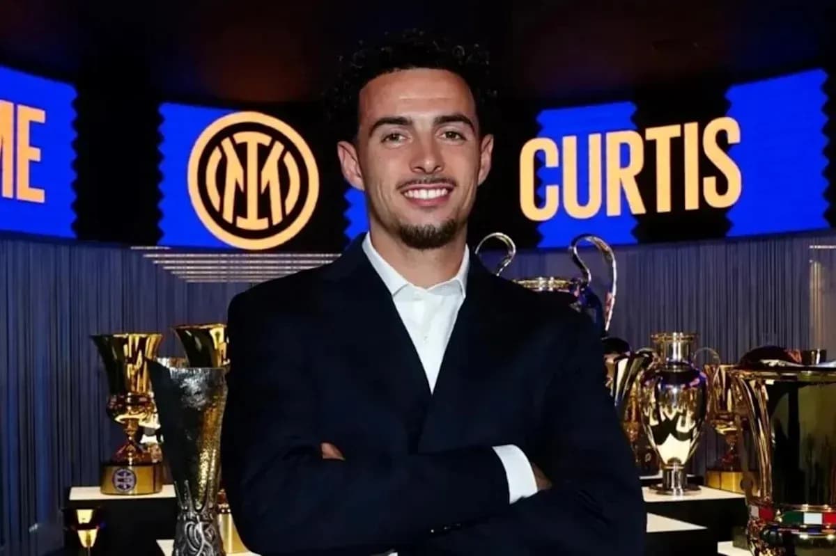 Man in suit smiling with trophies in background