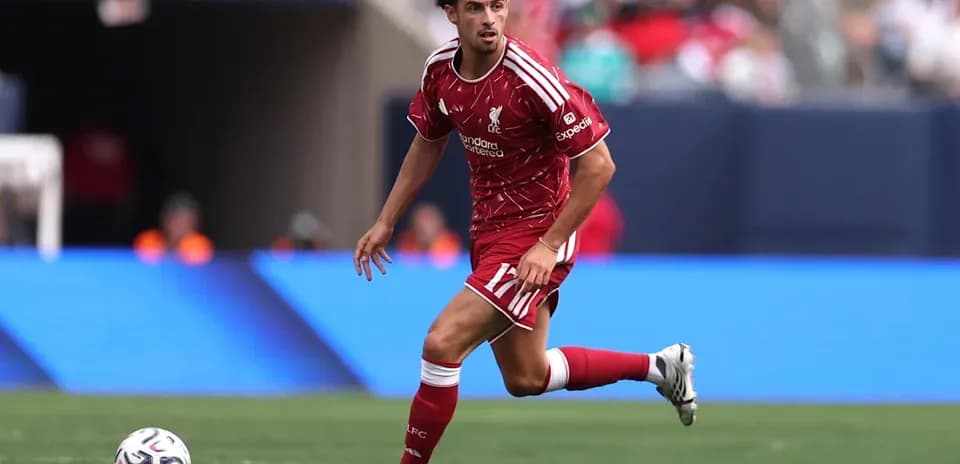 Player in Liverpool kit dribbling ball on field
