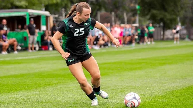 Player number 25 kicking soccer ball on field