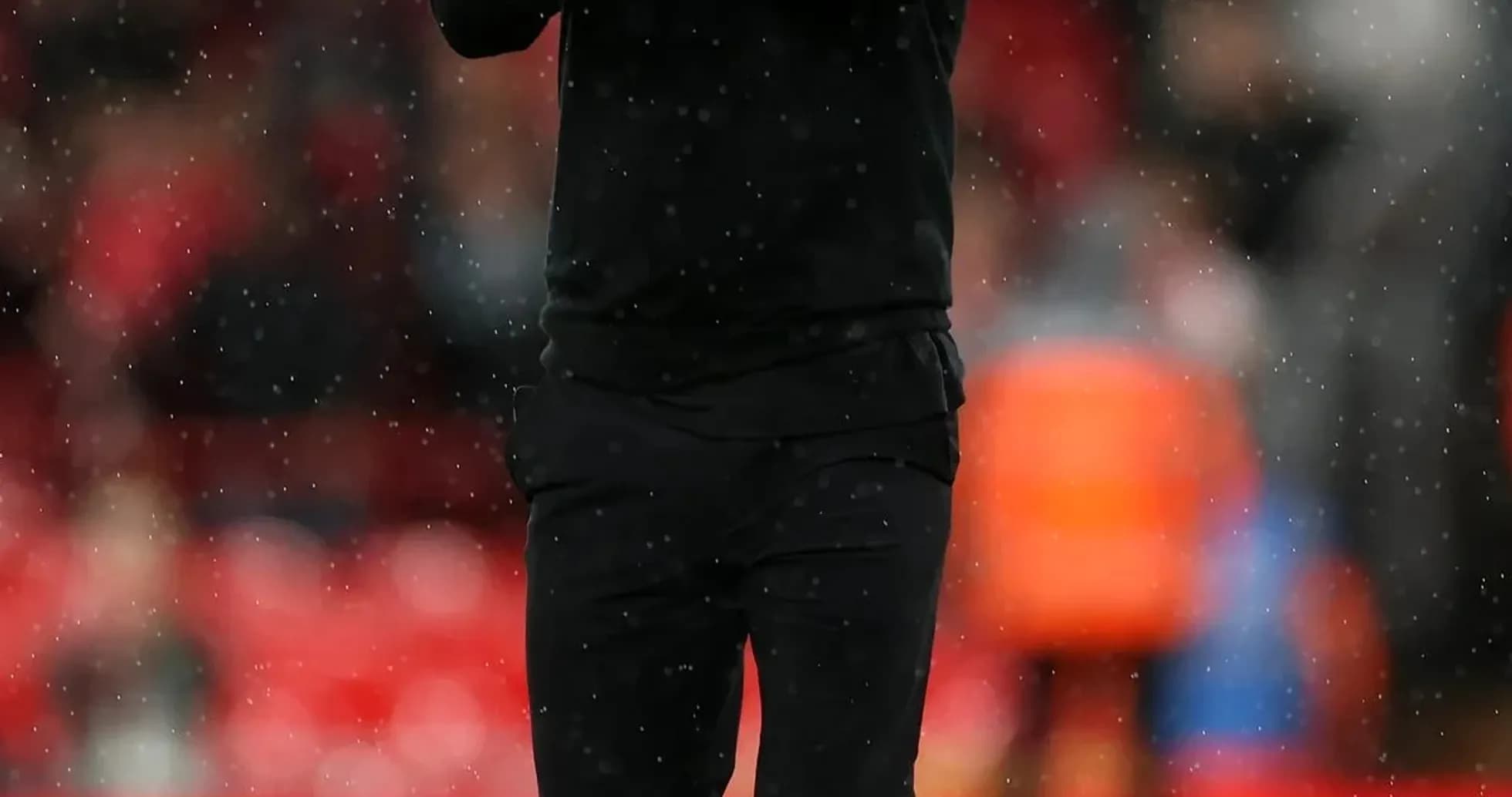 Manager applauding fans on rainy pitch