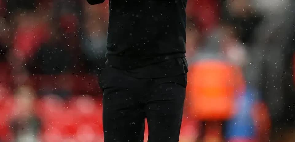 Manager applauding fans on rainy pitch