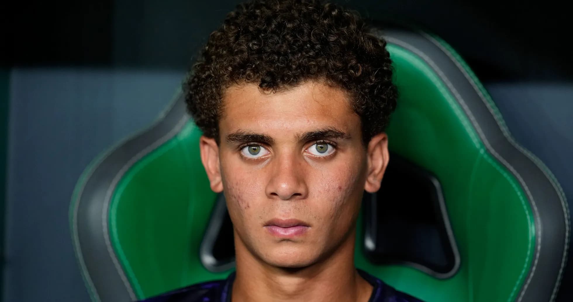 Young player sitting on a green gaming chair