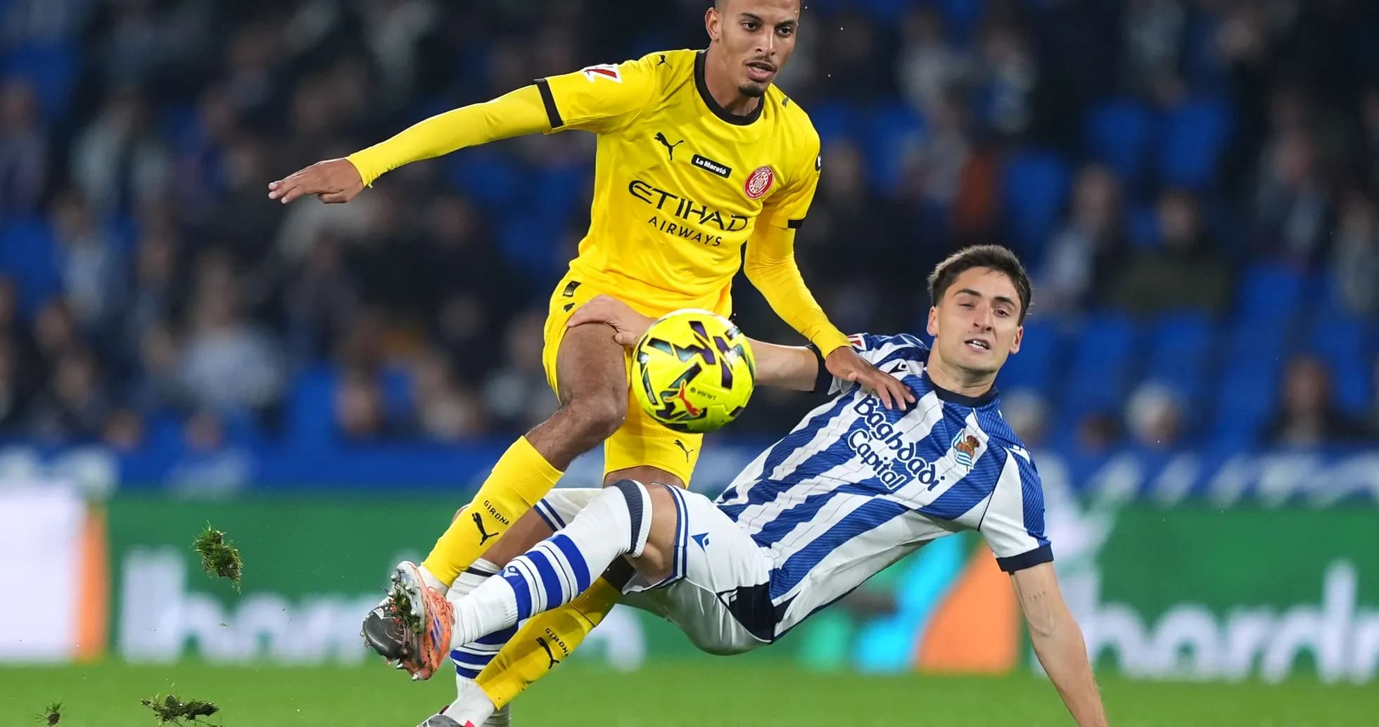 Girona player competing for the ball against Real Sociedad