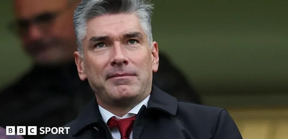 Man in suit observing from the stands at a match