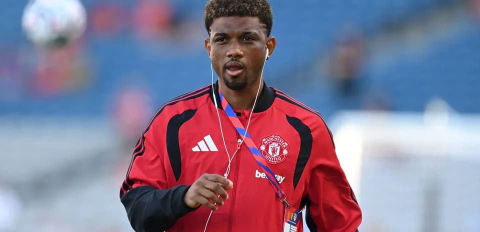 Player walking on pitch in Manchester United tracksuit