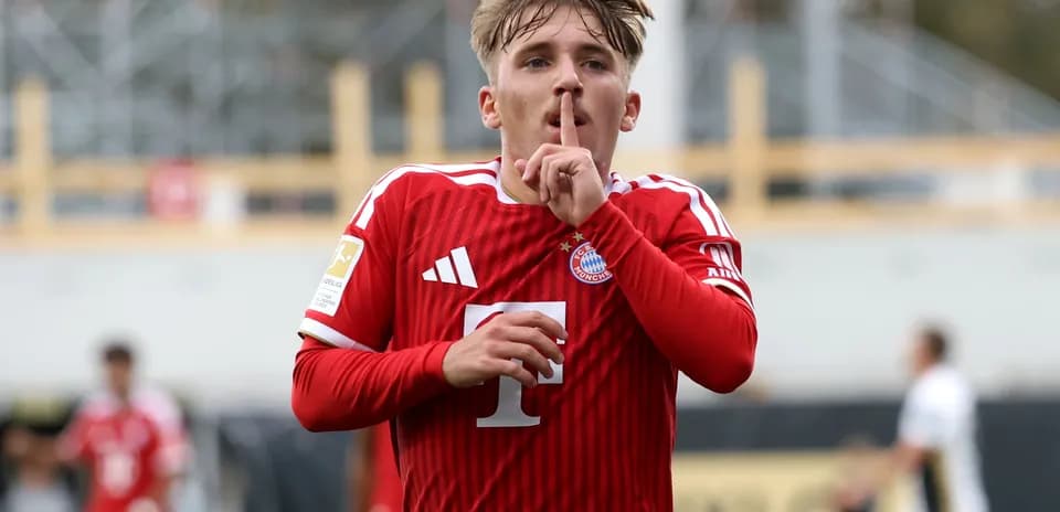 Player celebrating with shushing gesture in red jersey