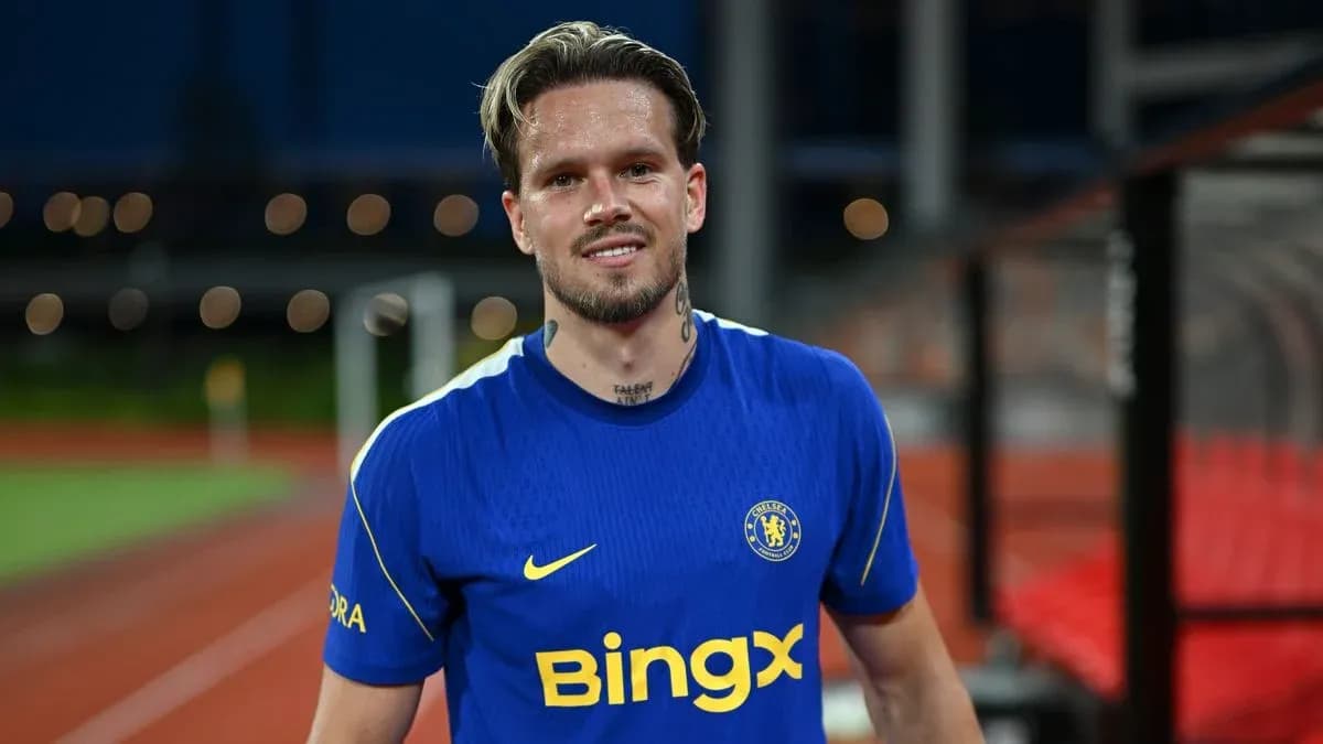 Player in blue Chelsea jersey smiling on pitch
