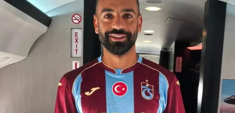 Player wearing Trabzonspor jersey in airplane aisle