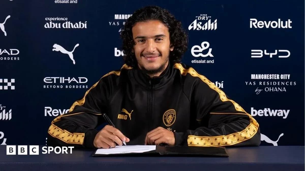 Player signing contract at press conference table